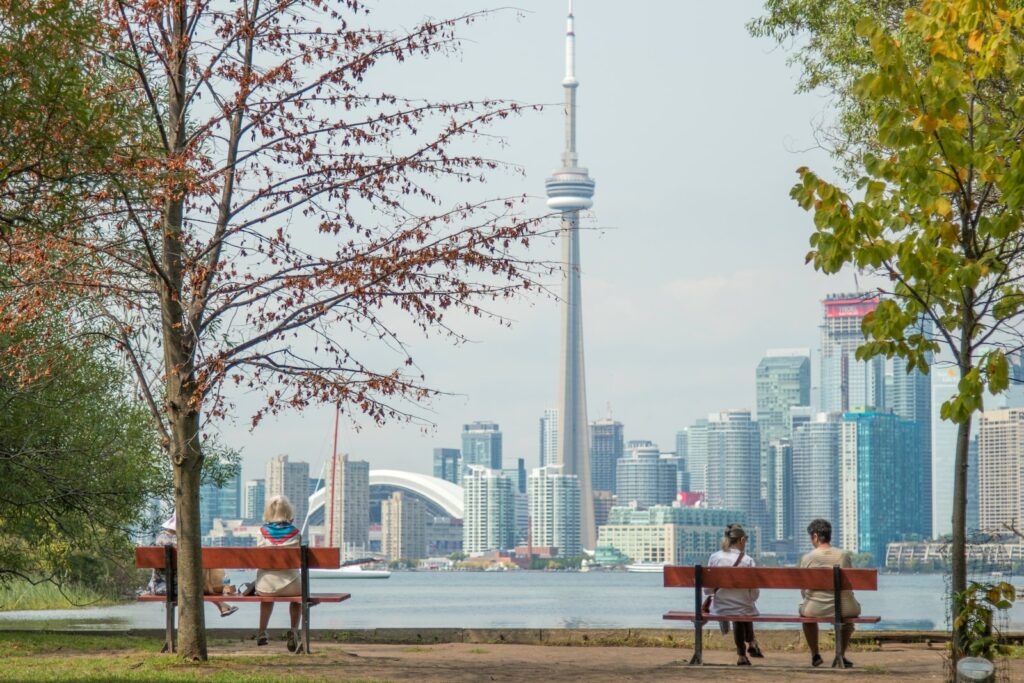 CN Tower in Toronto- four people sits on park benches across city scape
