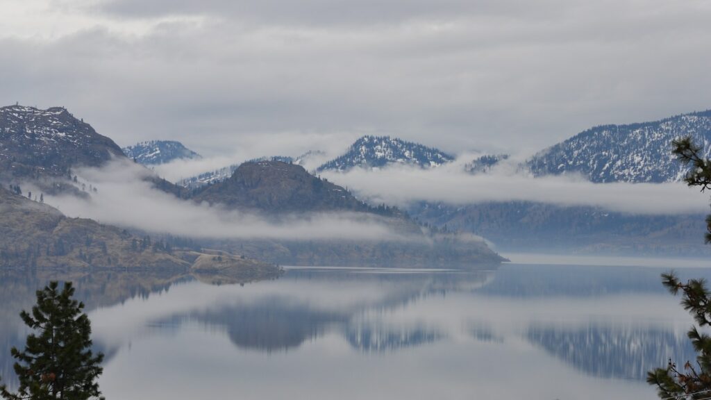 Peachland - body of water near mountain under white clouds during daytime